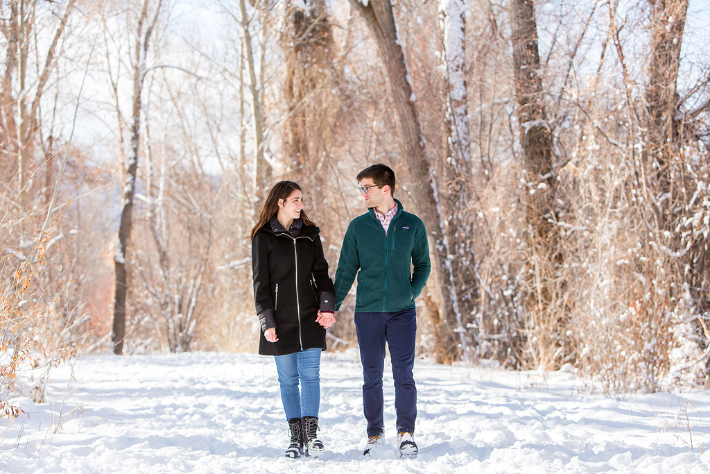 Dan and Elizabeth walk through a snowy forest after getting engaged near Aspen.