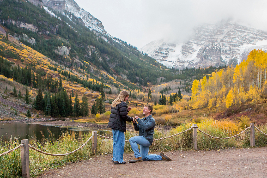 Jackson kneels in front of Maroon Lake as he proposes to Claire in Colorado.