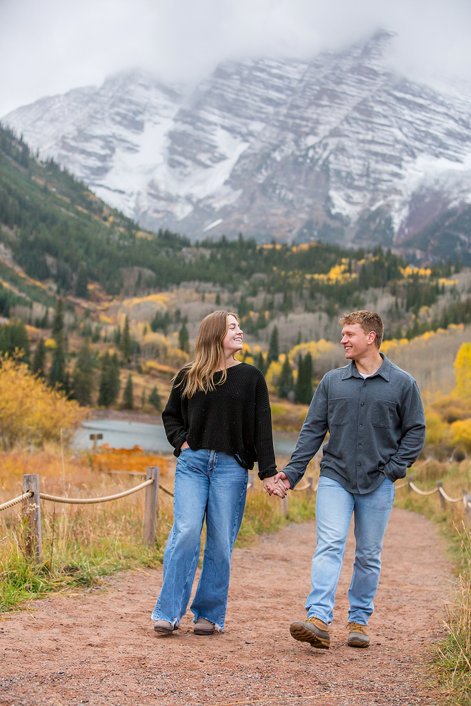 Jackson and Claire walk with the Maroon Bells Peak behind them after getting engaged.