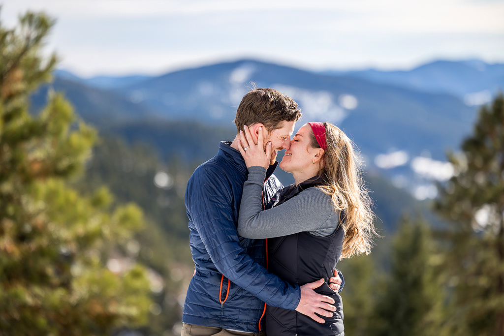 Hannah and Sam kiss with a mountain view behind them in Colorado after their engagement.
