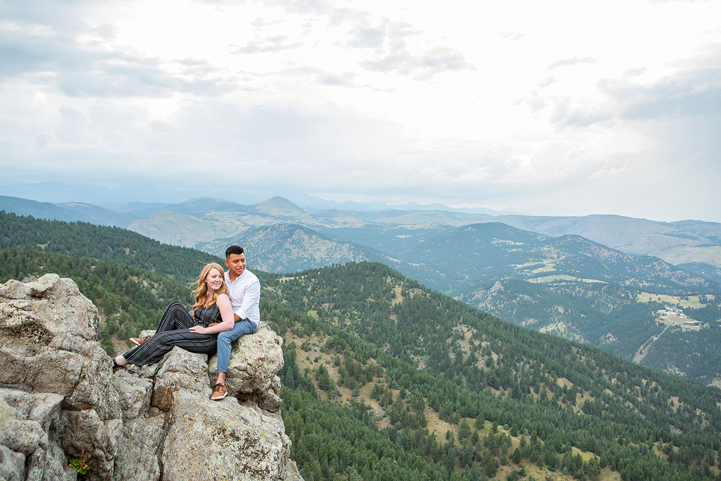 Luis and Nicole sit on the edge of a cliff at Lost Gulch Overlook taking in the mountain view.