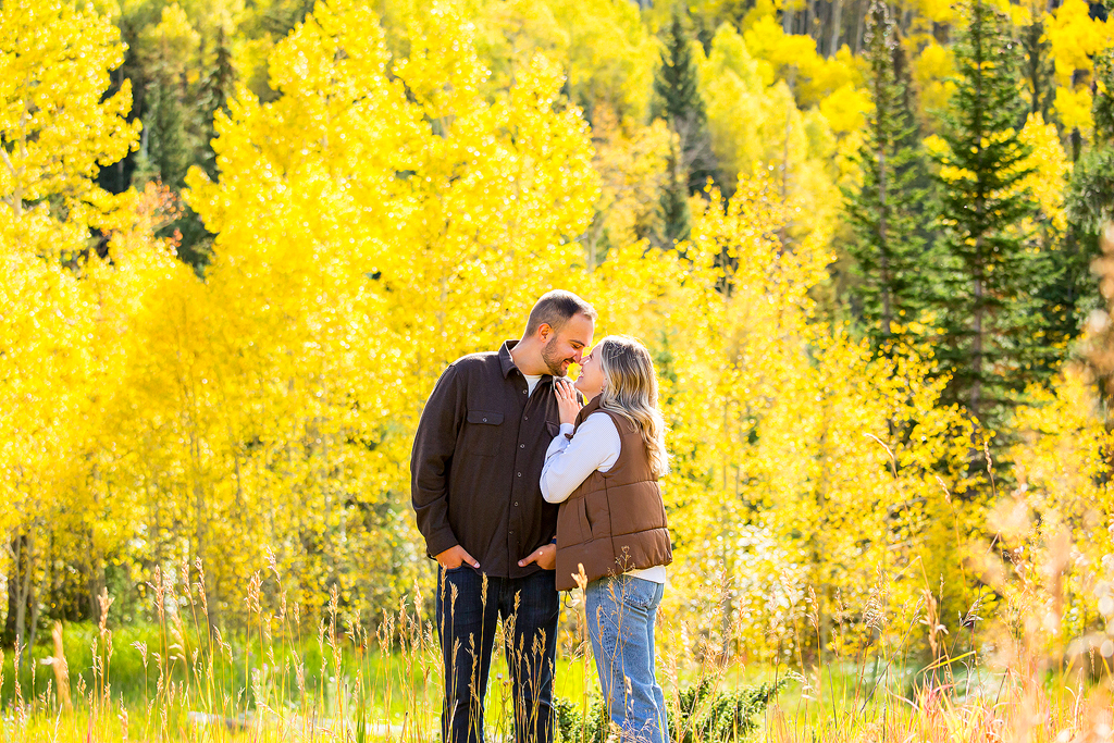 Vibrant yellow fall colors glow behind Alex and Nick as they snuggle at Ashcroft Ghost Town after getting engaged.