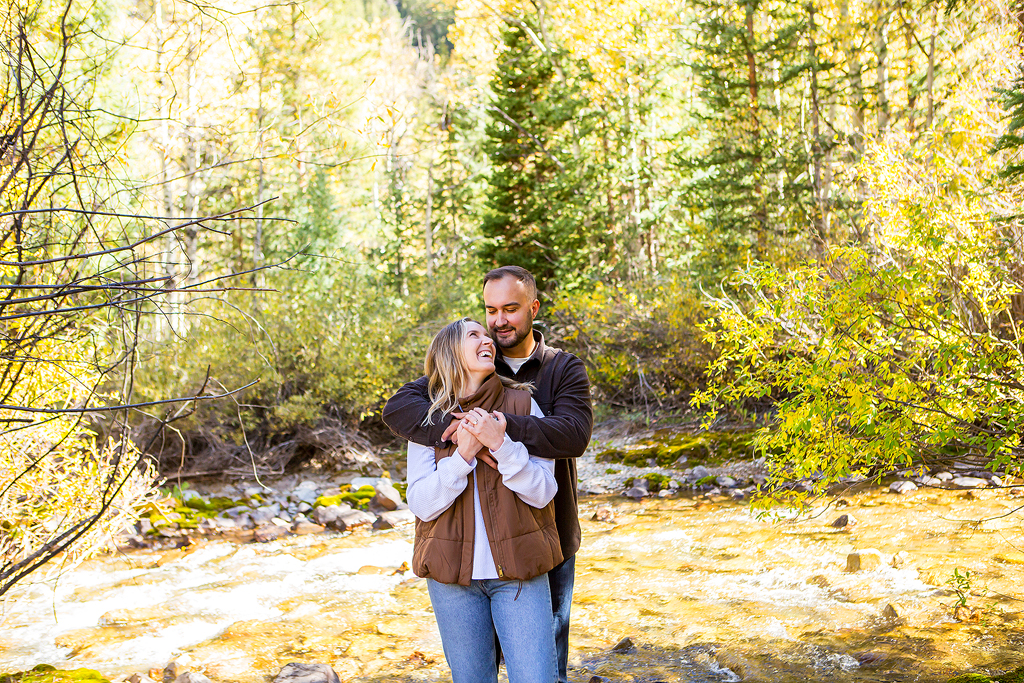 Nick hugs Alex in front of a creek after their Colorado surprise proposal in the fall.
