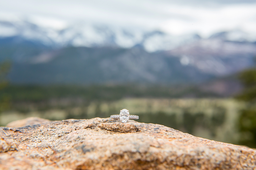 Close-up of Lea's engagement ring with the mountains of RMNP in the background.