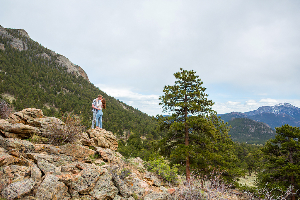 Noah and Lea stand on a rock at the 3M Curve scenic overlook during their engagement.
