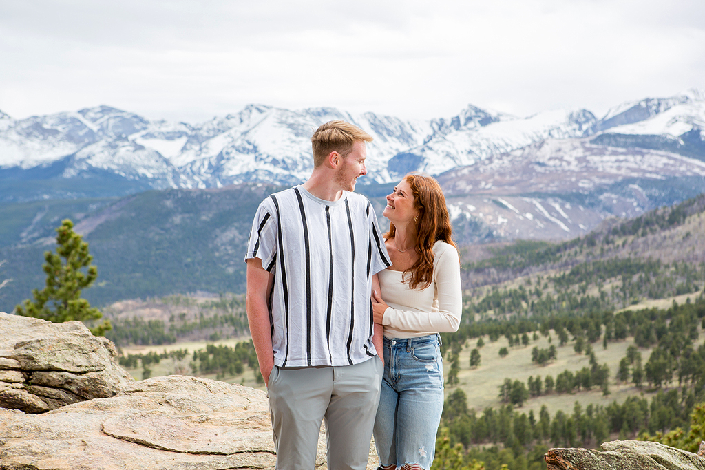 Lea hugs Noah's arm and shows off her engagement ring in Rocky Mountain National Park.