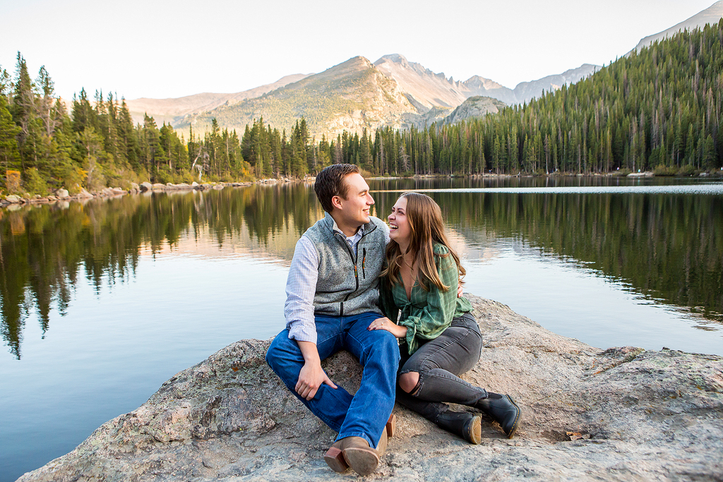 Will and Erika sit on a rock in the middle of Bear Lake with a mountain reflection behind them.
