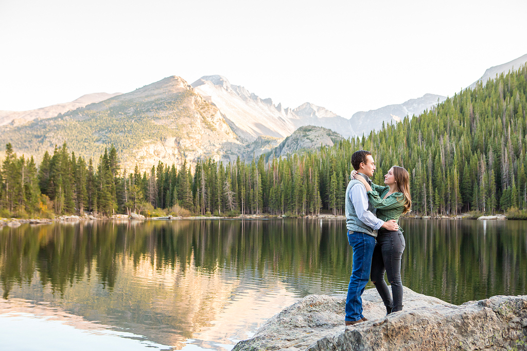 Will and Erika stand with a mountain reflection behind them in Rocky Mountain National Park.