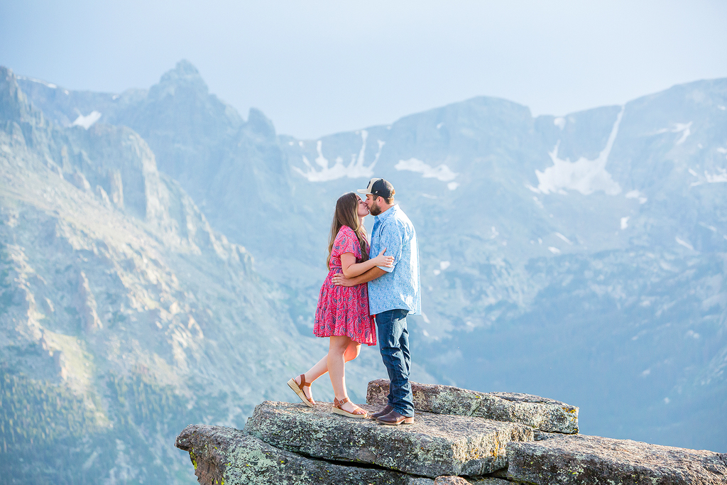 Couple kisses in front of the snow capped continental divide in Colorado.