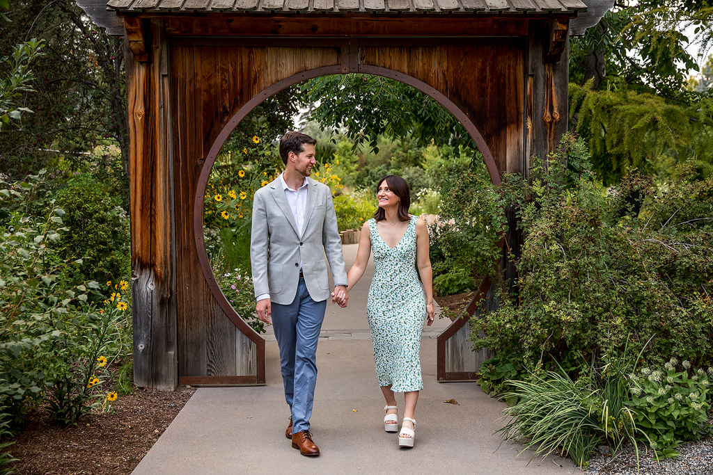 Couple at Denver Botanic Gardens walking down a path surrounded by greenery and flowers after their proposal.