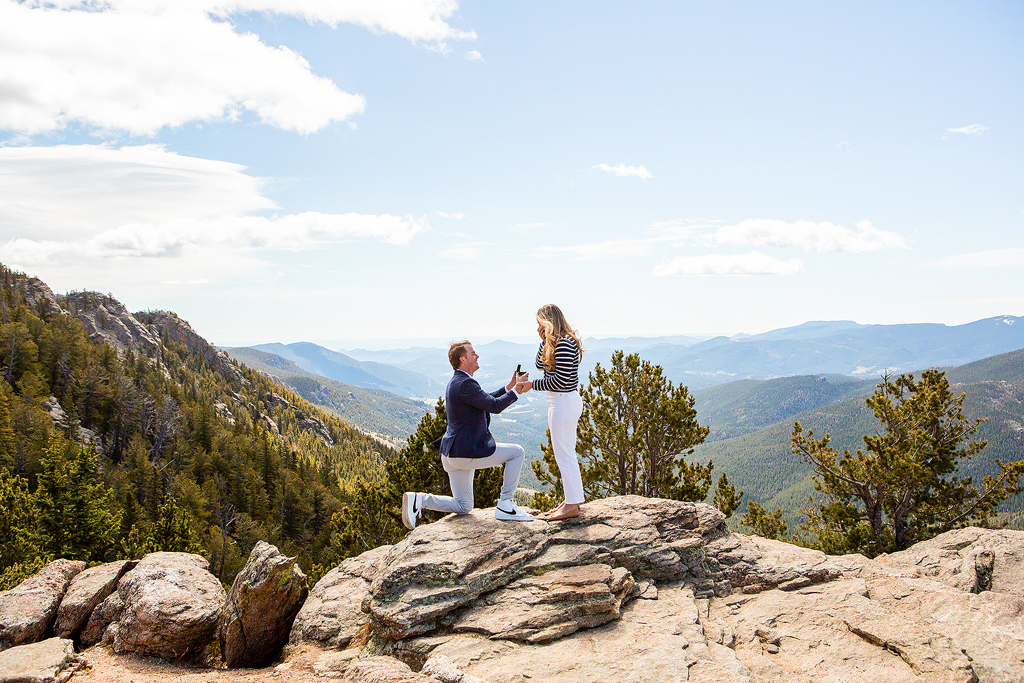 Ed kneels to propose at Juniper Pass in front of a panoramic mountain view.