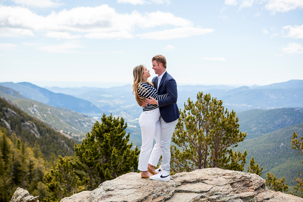 Couple stands on rocky cliffs at Juniper Pass after their surprise proposal.