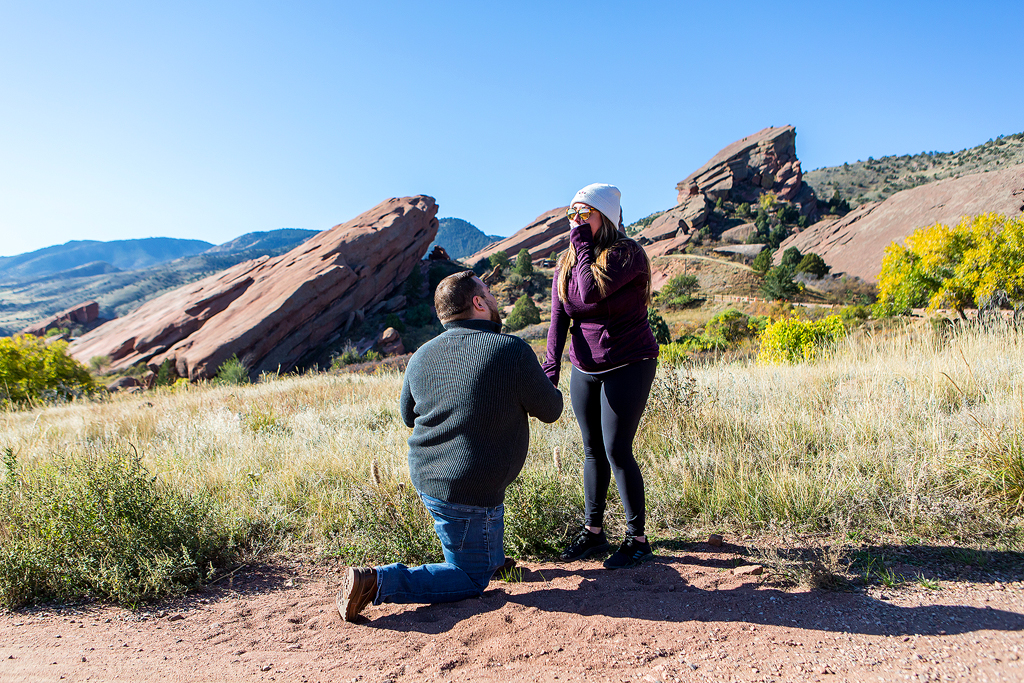 Red Rocks Proposal, Cory kneels in front of the rock formations.